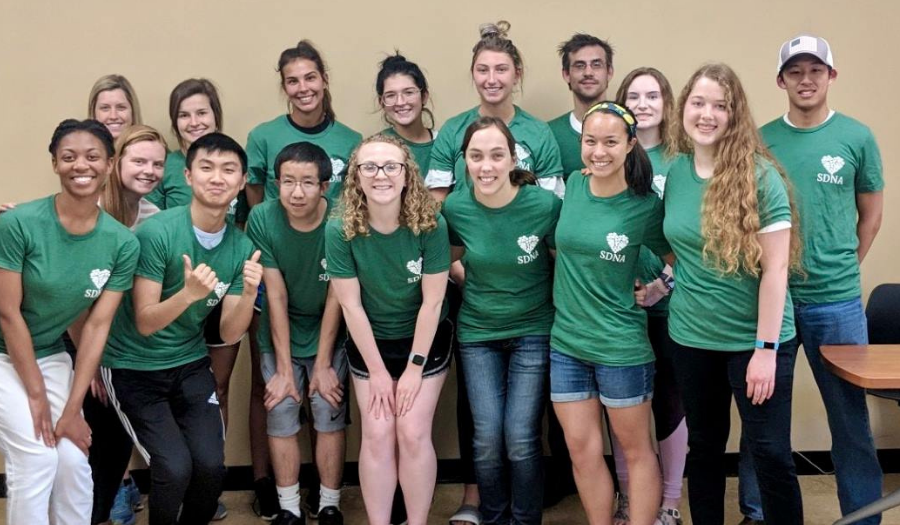 Group of students pose together in green shirts